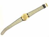 watch on a white surface with a black strap and a gold buckle