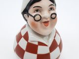une figurine en céramique représentant un garçon portant des lunettes et un chapeau