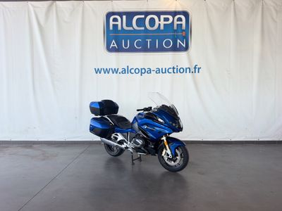 une moto bleue garée devant un mur blanc