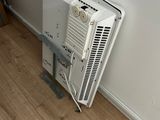 a white air conditioner sitting on the floor next to a wall