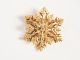 an image of a gold snowflake brooch on a white surface