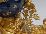 an image of a gold and blue clock sitting on top of a table