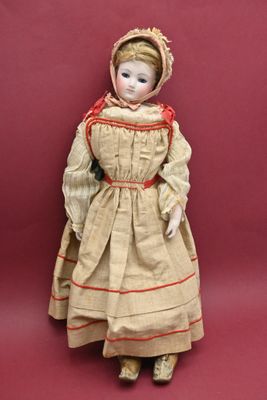 an antique doll of a woman in a dress and bonnet