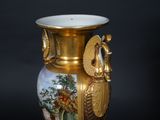 a gold vase with a painting on it sitting on a table