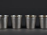 a set of six silver cups sitting on top of a table