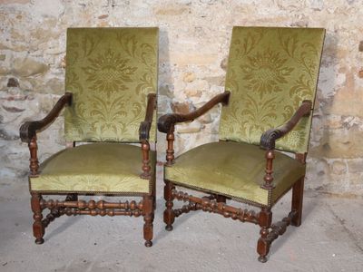 pair of green upholstered chairs in front of a stone wall