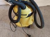 un aspirateur jaune muni d'un tuyau noir posé par terre