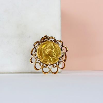une image représentant une bague en forme de pièce d'or posée sur un bloc de marbre