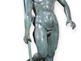 statue d'un garçon tenant une lance et un poisson, assis sur un rocher