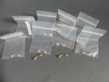 six sacs en plastique transparent munis de crochets dorés, posés sur une surface grise