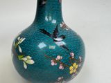 a blue vase with a bird on it on a table