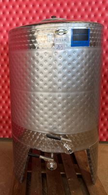 une grande cuve en acier inoxydable posée sur une palette en bois