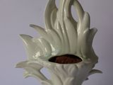 a white vase with a plant inside of it on a table