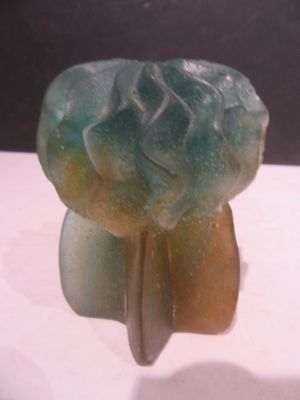 une sculpture en pierre verte et jaune posée sur une surface blanche
