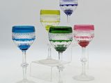 several different colored wine glasses sitting on top of a white table