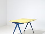 a yellow and blue table in a white room with a white wall