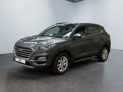 un SUV gris garé dans un showroom, avec une horloge accrochée au mur