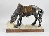 statue représentant un cheval buvant de l'eau dans un bol posé sur un socle en pierre