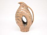 a brown vase with a curved handle on a white surface