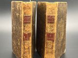 two old books are sitting on a table with a black background