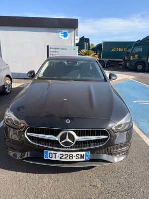 une voiture noire garée sur un parking à côté d'un camion blanc