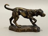 statue en bronze représentant un chien courant sur un rocher, sur fond blanc