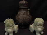 three figurines sitting next to a vase on a table