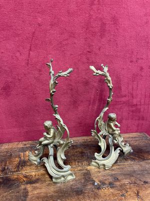 pair of antique brass figurines on a wooden table against a pink background
