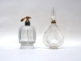 une paire de flacons de parfum en verre transparent rehaussés de touches dorées sur fond blanc