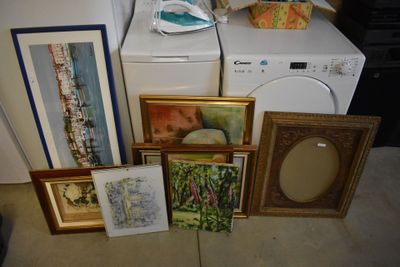 a lot of framed pictures on the floor next to a washing machine