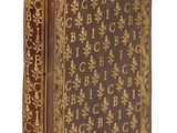 un vieux livre avec des lettres dorées sur fond blanc