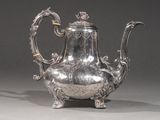 une théière ancienne en argent, ornée de motifs élaborés sur fond gris