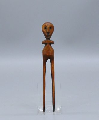 une petite sculpture en bois représentant une personne dont la tête est dotée d'un visage