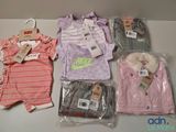 several baby clothes sitting on top of a table next to a hanger