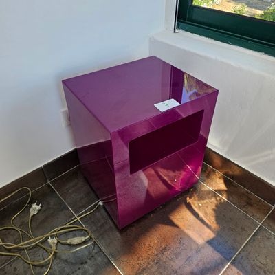 une table violette avec un plateau en verre, placée devant une fenêtre