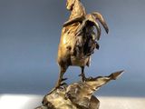 bronze statue of a rooster on a rock with a bird on top