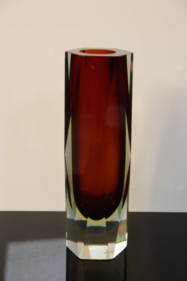 a red glass vase sitting on a black table