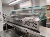 stainless steel counter top in a commercial kitchen with a glass display case