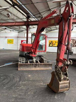 une pelleteuse rouge qui se trouve à l'intérieur d'un bâtiment