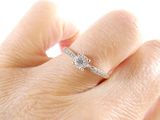 a woman ' s hand with a diamond ring on it
