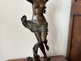 bronze statue of a woman holding a bird on top of a wooden table