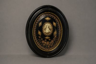 assiette noire et dorée ornée de l'image d'une femme entourée d'une couronne de fleurs
