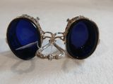 un gros plan sur une paire de boucles d'oreilles en verre bleu posées sur une surface blanche
