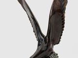 une image représentant une statue en bronze d'un oiseau posé sur une souche d'arbre