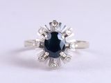 gros plan d'une bague avec un saphir bleu entouré de diamants blancs