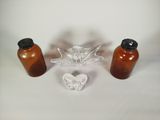 trois bouteilles et un saladier en verre posés sur une table
