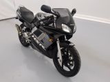 a black motorcycle parked in a room with a white wall