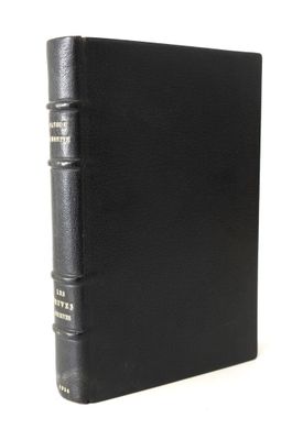 un vieux livre à la couverture noire posé sur une table blanche