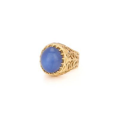 gros plan d'une bague en or avec une pierre bleue