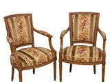 paire de fauteuils de style Louis XVI aux accoudoirs rembourrés d'un motif floral